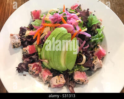 Seared tuna on salad greens, topped with avocado and vegetables Stock Photo