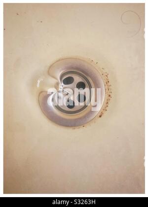 Water draining down an old plug hole in a bath Stock Photo