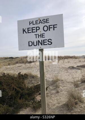 A sign on the beach reading “please stay off the dunes.” Stock Photo