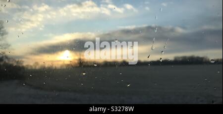Sunrise through a car window with droplets on the outside. Stock Photo