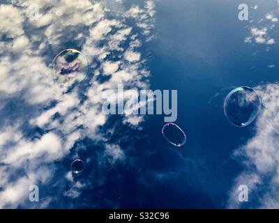 Soap bubbles floating away against a deep blue summertime sky. Stock Photo