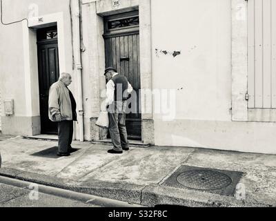 Two older Frenchmen conversing on the street in Provence, France. Stock Photo