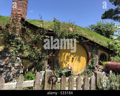 Photo from the movie set of the hobbit. Yellow round door and small house with greenery.