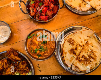 Selection of Indian restaurant food in bowls including chicken tikka masala naan breads rice and fries Stock Photo