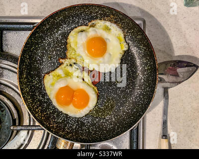 Fried eggs in a pan including a double yolk egg Stock Photo