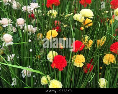 A full frame nature background image of realistic, artificial wild flowers in a colourful garden or meadow with copy space Stock Photo