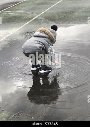 Boy jumping in muddy puddles Stock Photo