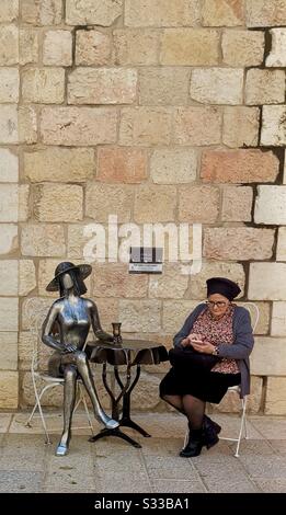 A woman sitting by a sculpture in Mamilla shopping complex. Stock Photo