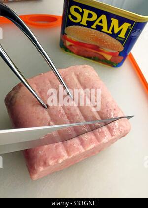 Spam luncheon meat being carved on a cutting board Stock Photo