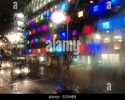 Multicolored lights on building in rain blur in London street view from bus Stock Photo