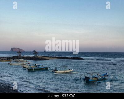 Traditional outrigger fishing boats moored off the beach at sunset, Candidasa, Bali, Indonesia Stock Photo