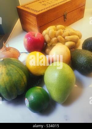 Still life of fruit and vegetables with a old-fashioned wooden recipe box on a residential kitchen counter, USA Stock Photo