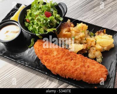 Breaded white fish with potatoes and fresh lettuce salad. Stock Photo