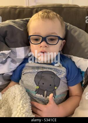 Baby toddler wearing prescription eye glasses. Baby is tires.