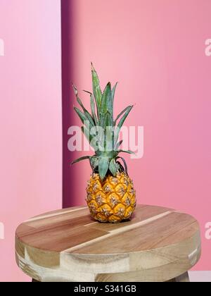 A mini pineapple on a table with a colorful background. Stock Photo