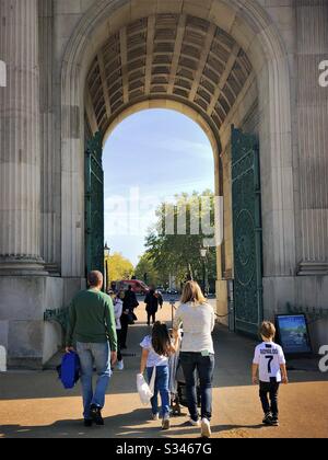 A young family are seen from behind, walking through gates of Wellington Arch, London. Stock Photo