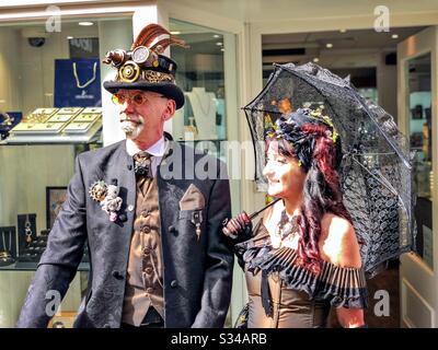 People in creative costumes during a cosplay event. Whitby Goth Weekend. Steampunk man and goth lady Stock Photo