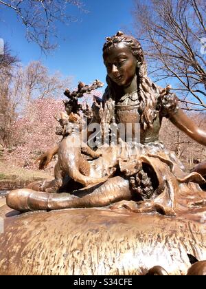 Alice in wonderland sculpture in central park is surrounded by blooming cherry trees in the spring, NYC, USA Stock Photo