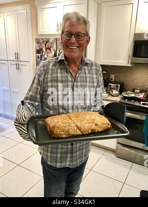 Man at home holding his finished recipe of salmon stuffed with crab wrapped in pastry dough fresh from the oven. Stock Photo