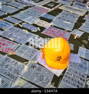 Yellow hard hat, symbolically worn by protesters echoing the original Umbrella Movement of 2014, and handwritten protest signs outside the Legislative Council building in Hong Kong, June 2019 Stock Photo