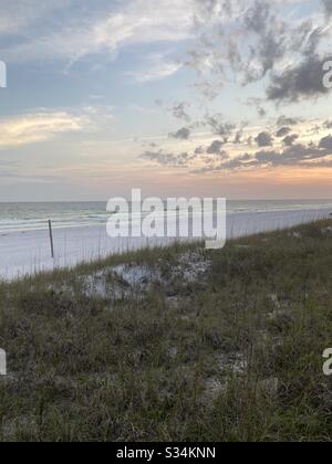 Soft sunset skies over the Gulf of Mexico water with green sand dunes Stock Photo