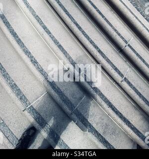 Shadow of person falls across a set of curved steps, edged with black bricks, outdoors, daytime Stock Photo
