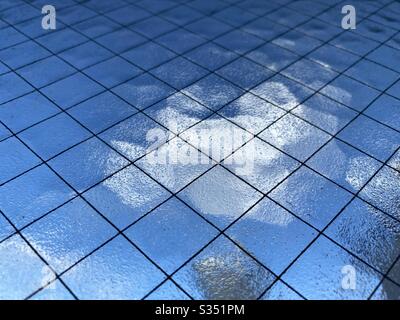 Close, angled view of opaque safety glass with wire mesh running through it, Indistinct blue sky and white cloud barely visible through it, creating abstract background texture. Stock Photo