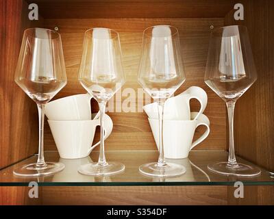 Wine glasses and contemporary cups are seen up close on a glass display shelf Stock Photo
