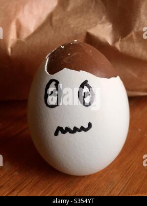 A broken eggshell with a face drawn on it and chocolate inside Stock Photo