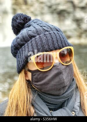 Woman in mask and sun glasses outside walking in a park Stock Photo