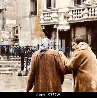 Two old women walking and talking on street Venice Italy Stock Photo