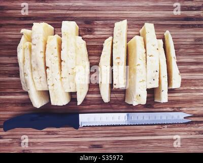Preparing a whole pineapple in the kitchen. Fresh and ripe fruit preparation. Ingredients for homemade pineapple salsa. On a wooden chopping board. Peeled and sliced with eyes removed Stock Photo