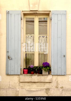 Window with potted plants and lace curtains in Remy de Provence, France. Stock Photo