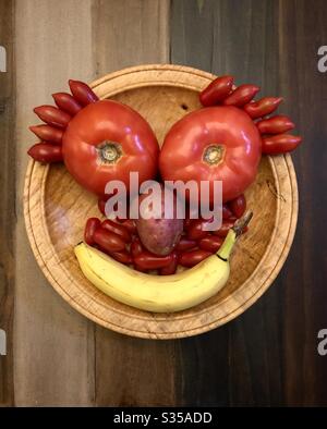 Happy face made out of vegetables and fruit on a wooden bowl and table top. Stock Photo