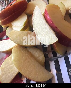 Slices of the fresh Fuji apple on a black and white striped plate Stock Photo
