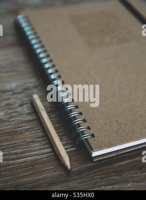 An old fashioned spiral notebook with pencil on a wooden desk top with vintage feel for a home office or study image with copy space Stock Photo