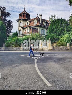 Woman walking her poodle in deserted street, Bern, Switzerland Stock Photo