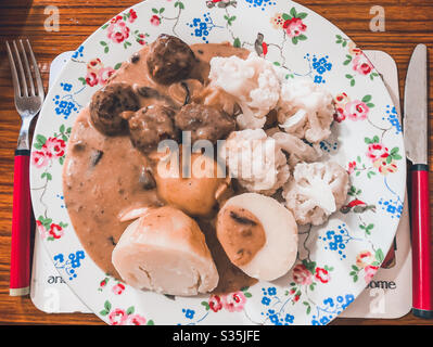 A plate of beef meatballs in a mushroom sauce with boils potatoes and cauliflower for dinner. Stock Photo