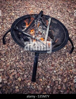Fire in a black metal fire pit, standing on gravel. Stock Photo