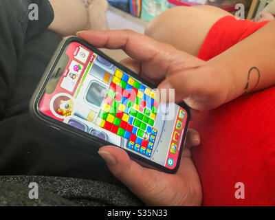 A woman plays a game on her mobile phone. Stock Photo