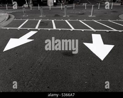 White arrows and crosswalk painted on black pavement. Bay Street, Emeryville, California. Stock Photo