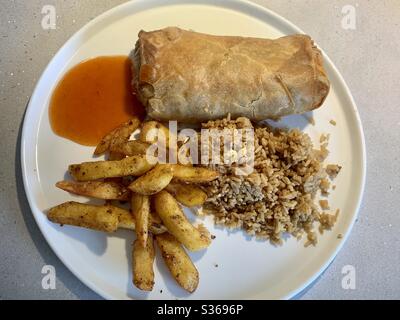 Chinese Takeaway. Pancake Roll, Egg Fried Rice, Chips and Sweet and Sour Sauce on a white plate. Stock Photo