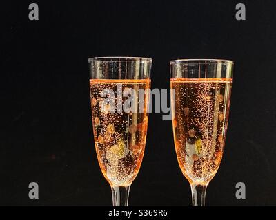 Pair of glasses full of pink champagne against a black background. No people. Space for copy. Stock Photo