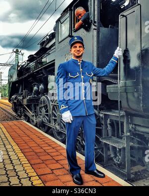 Uniformed Orient Express attendant with steam locomotive Stock Photo - Alamy