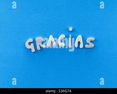 Gracias, thank you in spanish language composed with handmade wooden letters over blue color Stock Photo