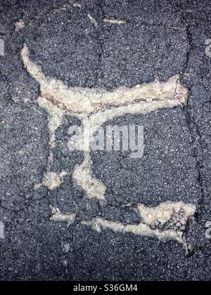 A texture abstract pattern of cracks and patches on asphalt on a road Stock Photo