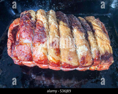 A joint of roast pork, fresh out of the oven on the roasting tray. Stock Photo