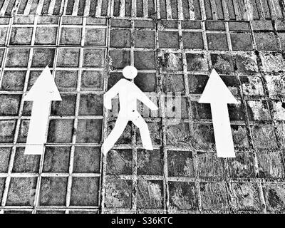 Pedestrian and arrows signs on pavement calling for people to keep right as a measure against spreading of covid-19 Stock Photo