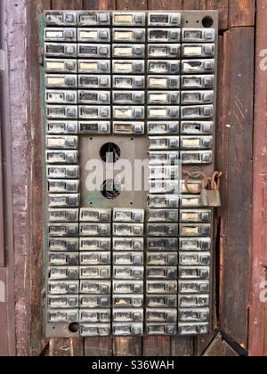 Buzzers for flats Old disused apartment block doorbell system or call box buzzers on wooden facade, row of doorbells Stock Photo