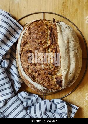 Freshly baked multigrain sourdough loaf cooling on rack Stock Photo